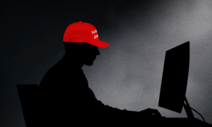 Silhouette of a man at a computer wearing a red MAGA hat 