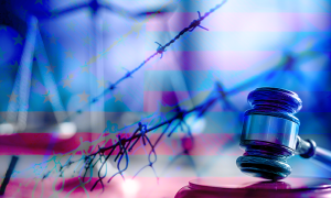 A gavel and barbed wire fence in front of an American flag