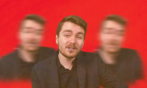 Image of Nick Fuentes superimposed upon three, blurrier Fuenteses in the background, with a red backdrop 