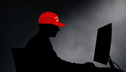 Silhouette of a man at a computer wearing a red MAGA hat 
