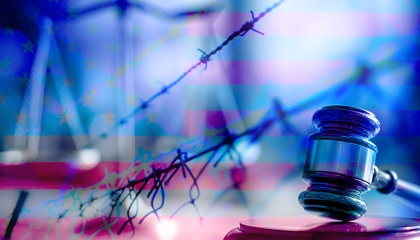 A gavel and barbed wire fence in front of an American flag