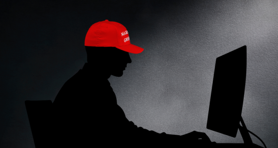 Silhouette of a man at a computer wearing a red MAGA hat 